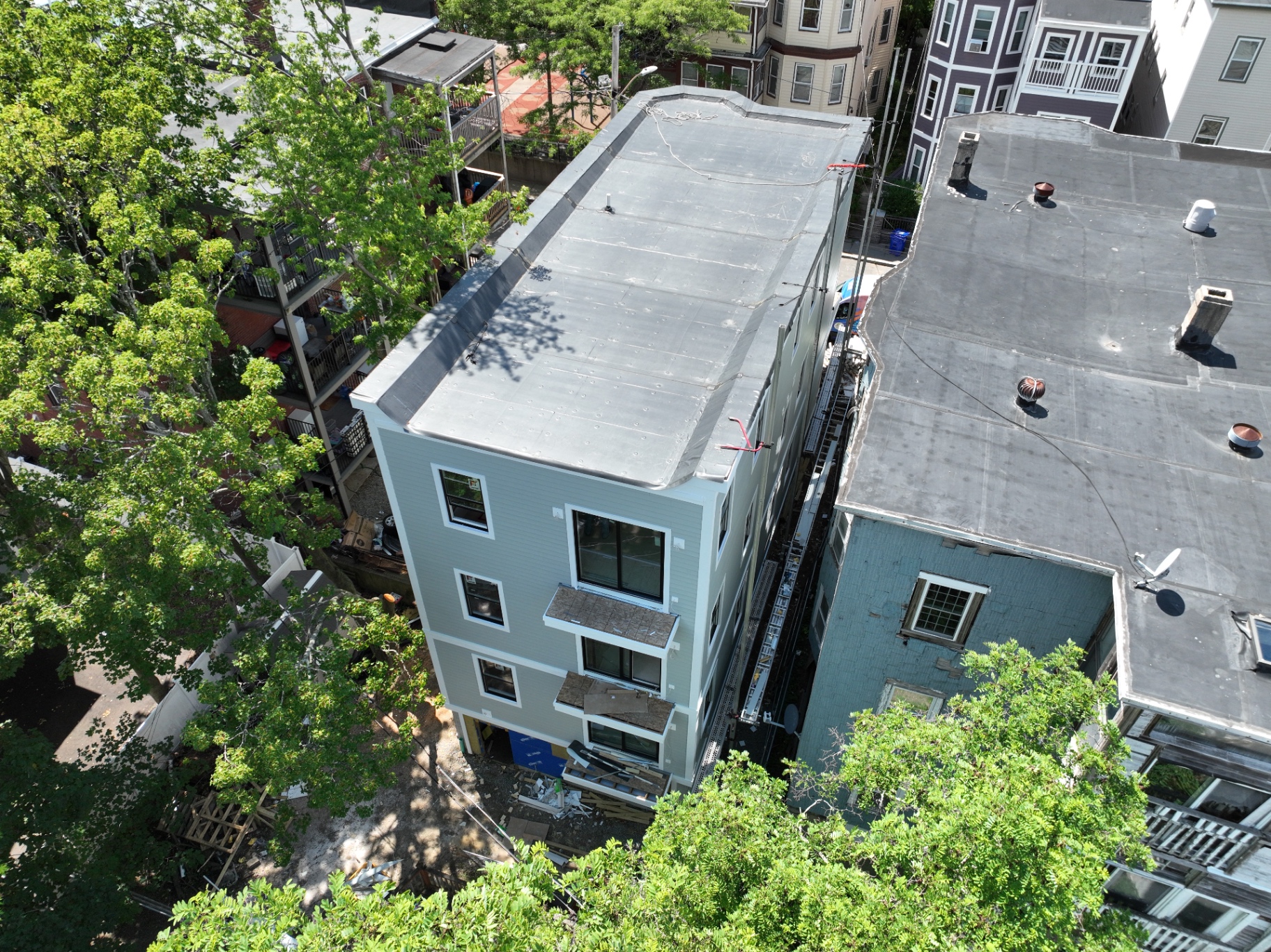 Side elevation complete: siding, trim, and roofing membrane installed.